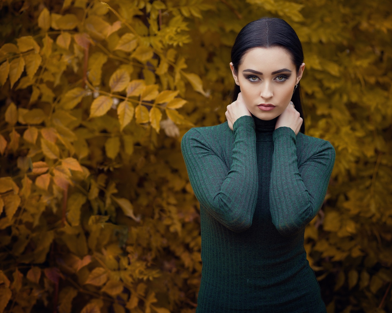 Красивая брюнетка позирует на фоне желтых листьев