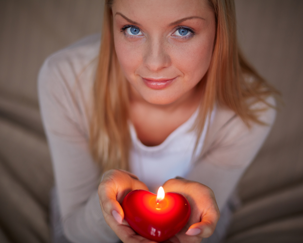 Красивая девушка держит в руках свечу в форме сердца