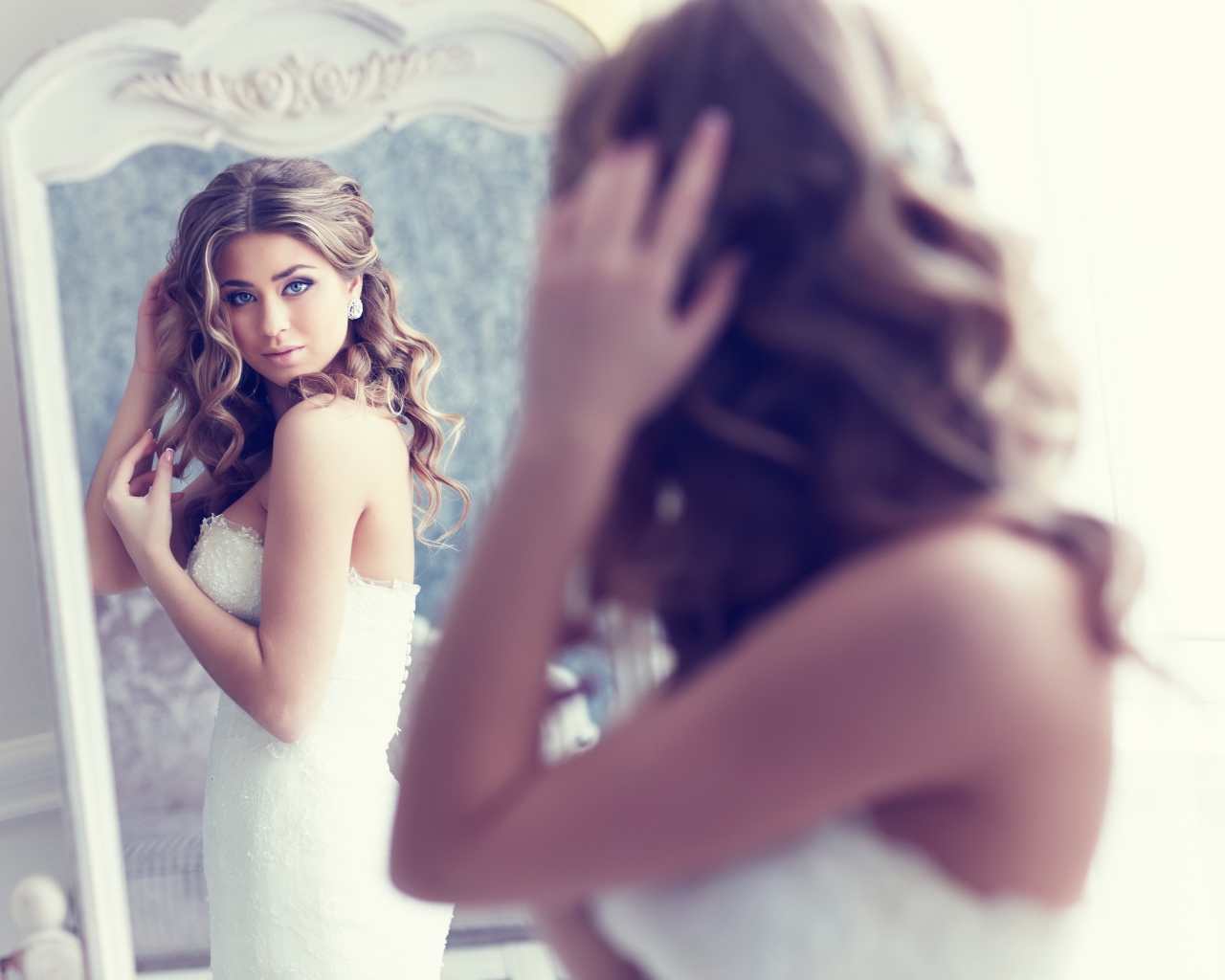 Красивая девушка в свадебном платье смотрит в зеркало 