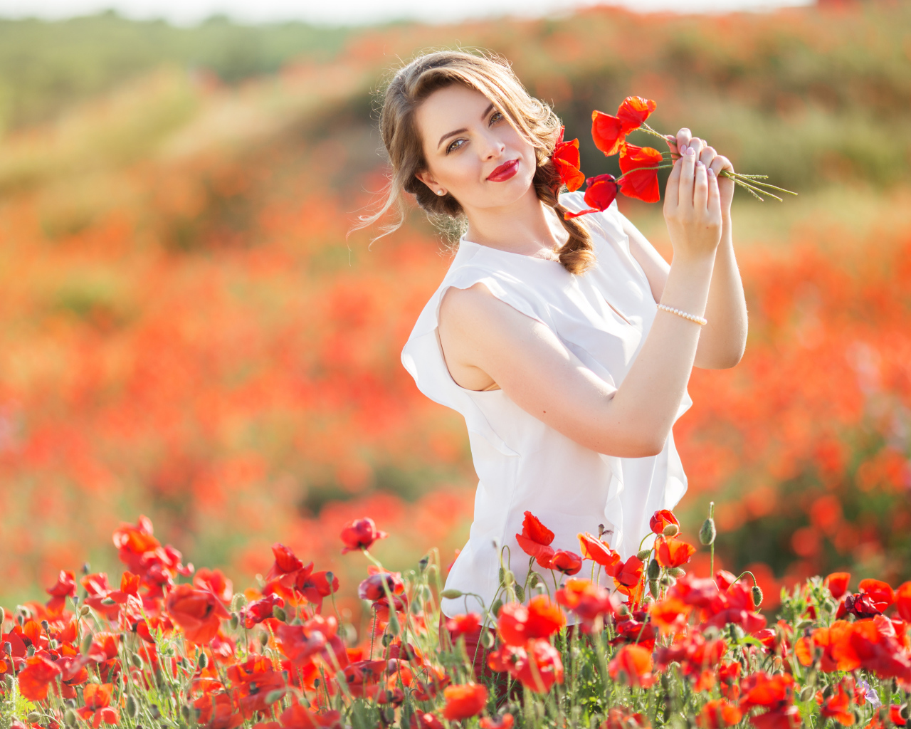 Красивая девушка в белом платье с букетом маков в руках
