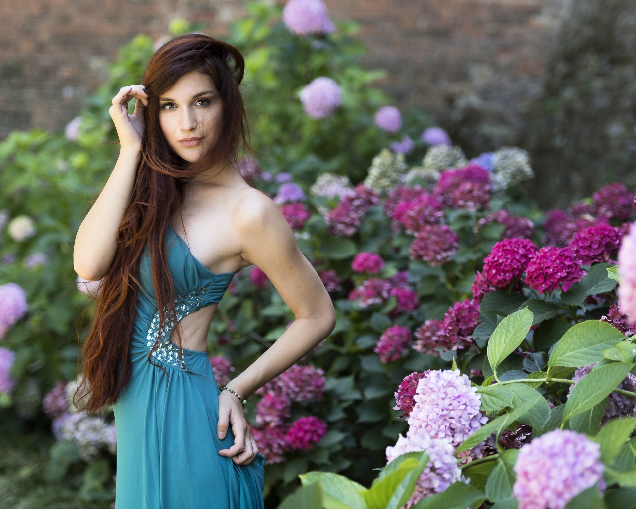Красивая девушка модель в зеленом платье рядом с цветами гортензии