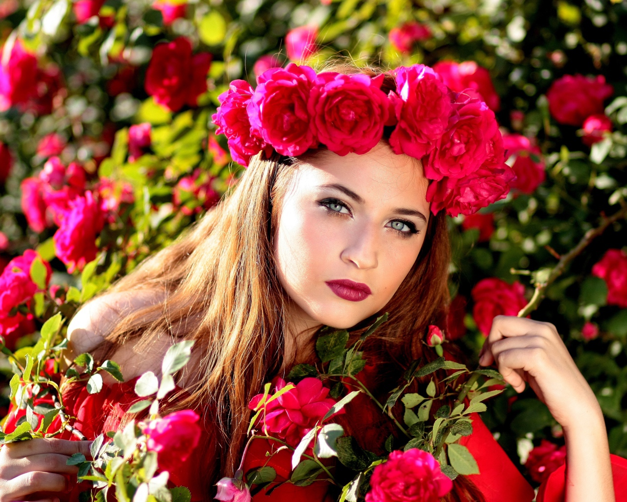 Красивая девушка с венком из красных роз на голове 