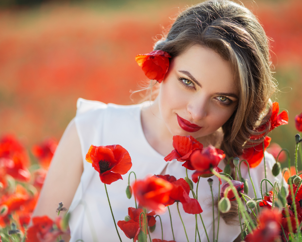 Красивая девушка с выразительным взглядом на поле с красными маками