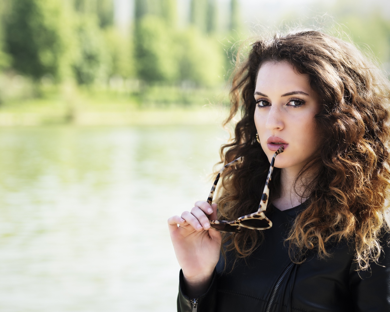 Красивая девушка с волнистыми волосами с очками в руках 