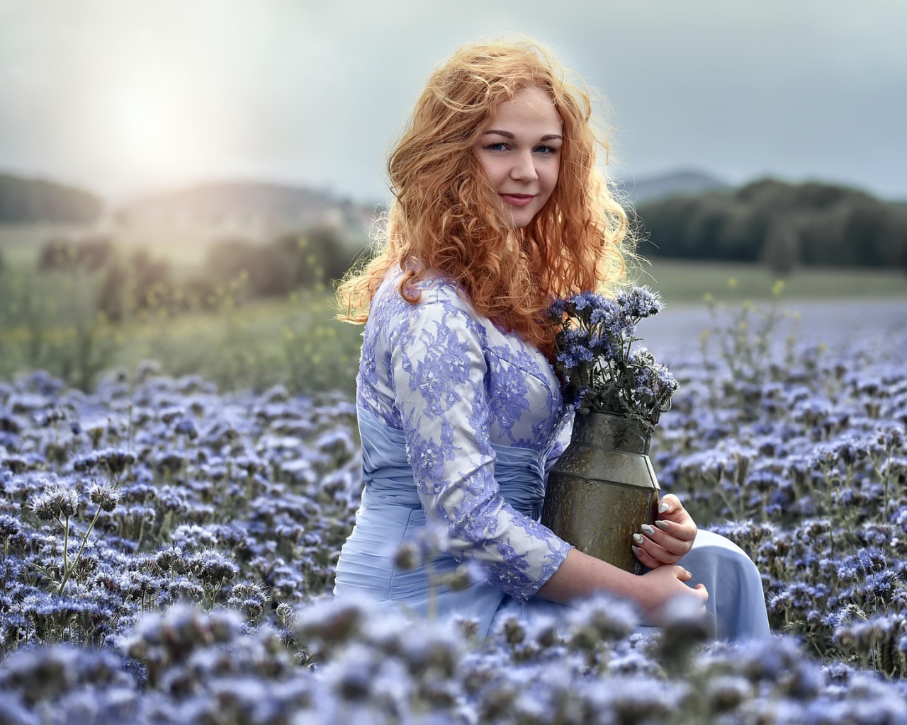 Красивая рыжеволосая девушка собирает цветы