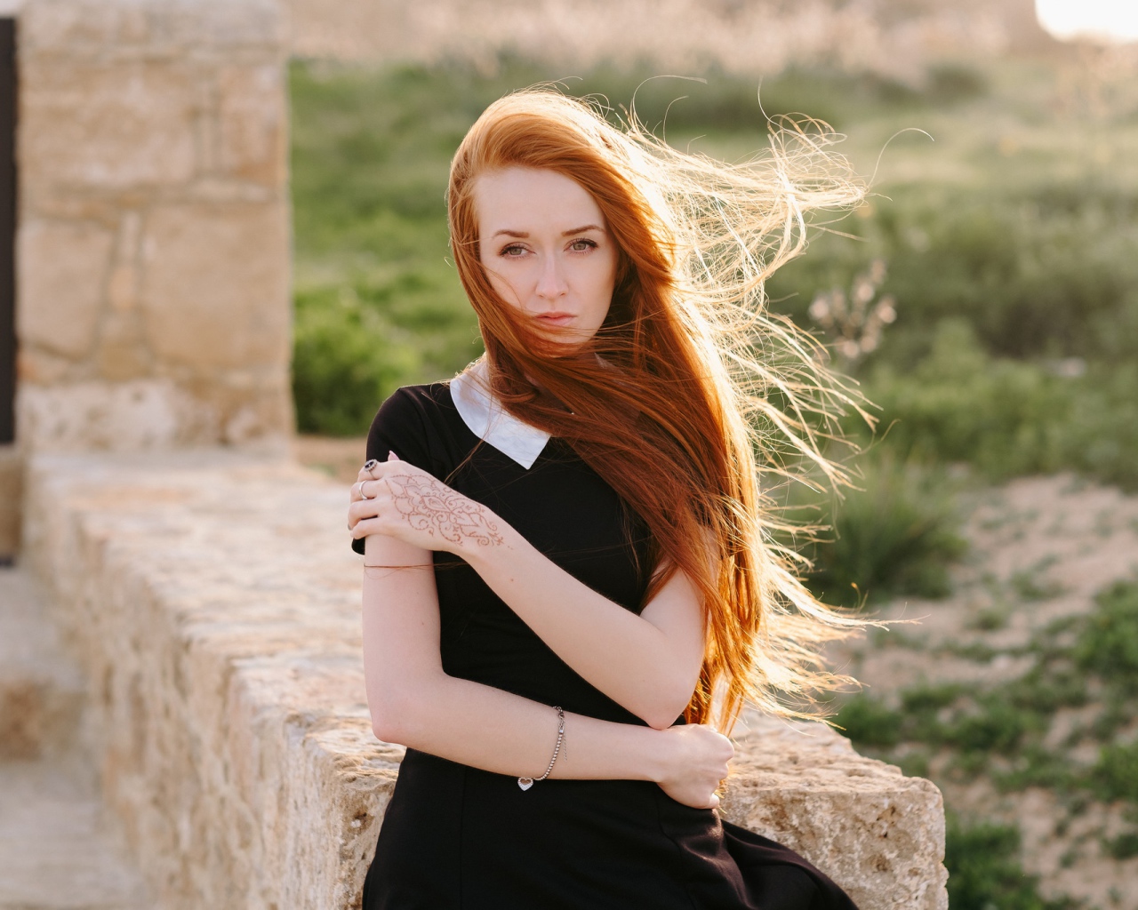 Красивая рыжеволосая девушка в черном платье с рисунком на руке