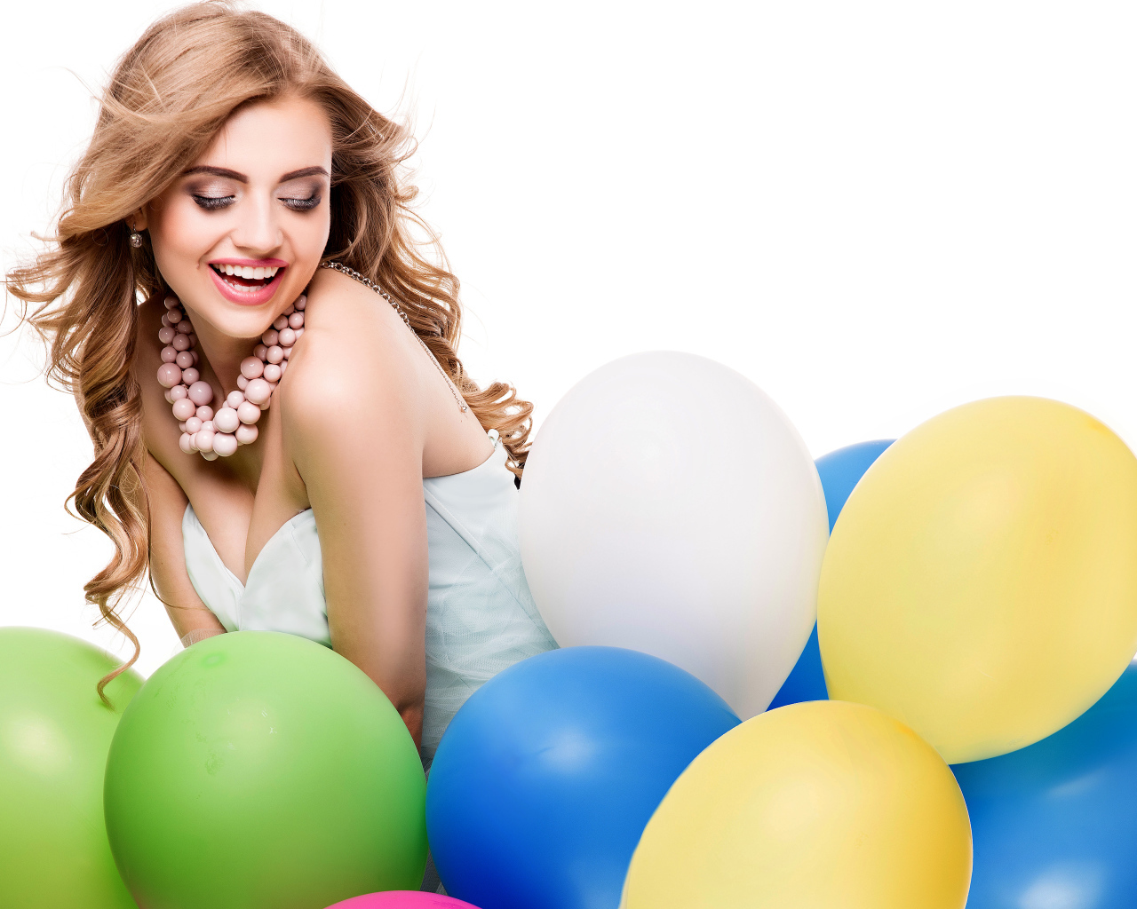 Красивая улыбающаяся девушка с разноцветными шариками на белом фоне