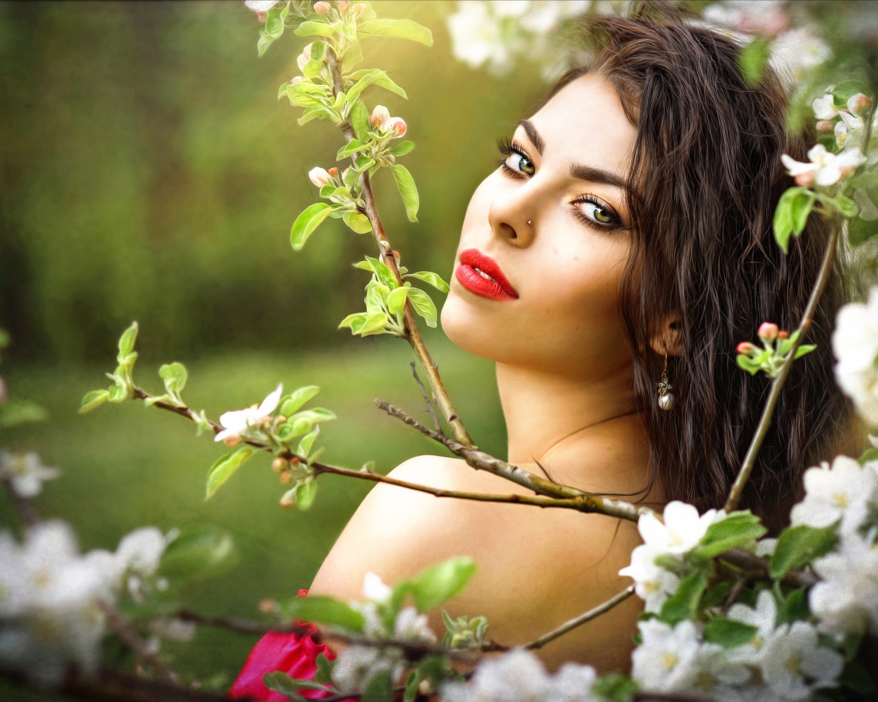 Красивая молодая девушка в ветках цветущей яблони 