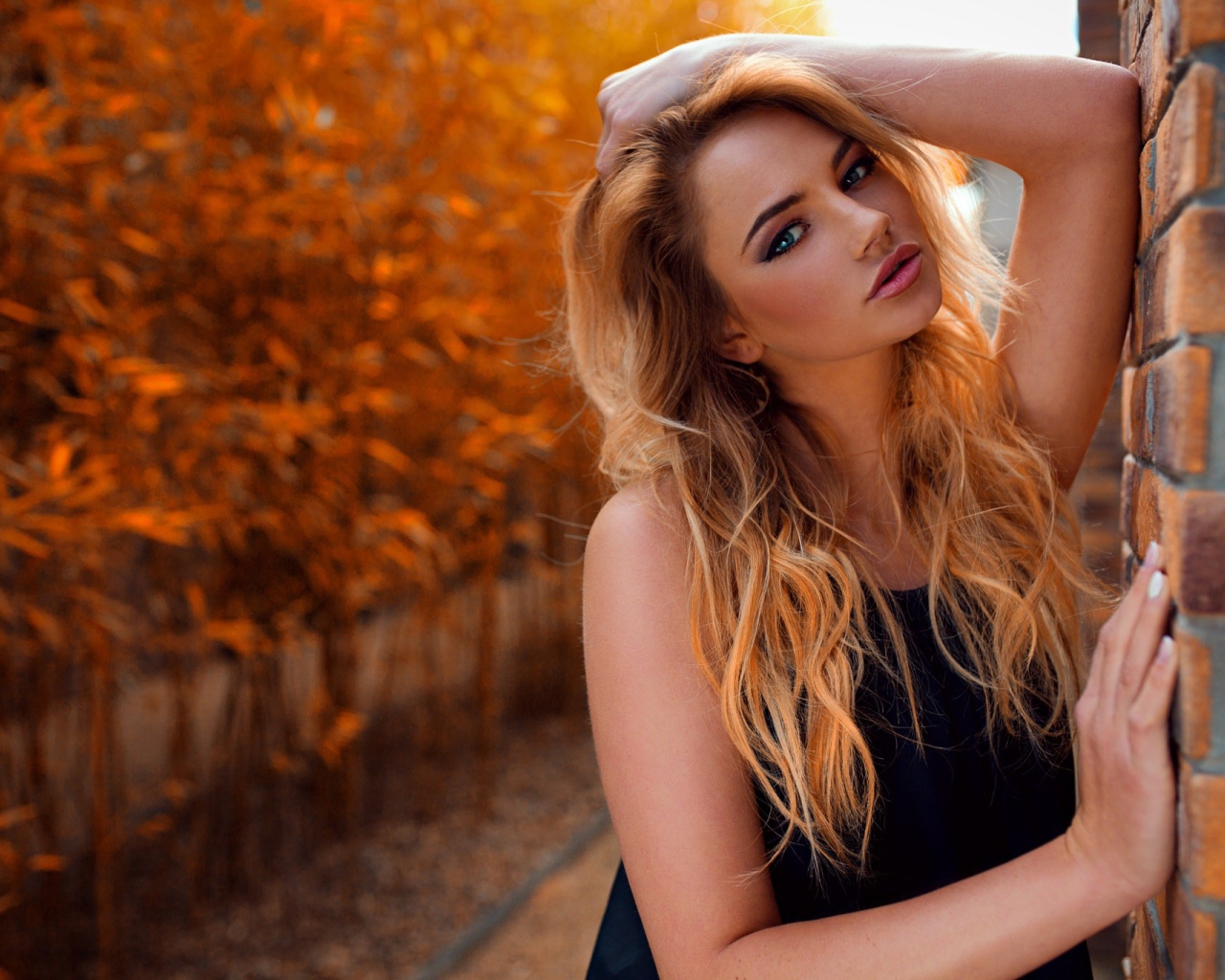 Голубоглазая девушка блондинка у стены 