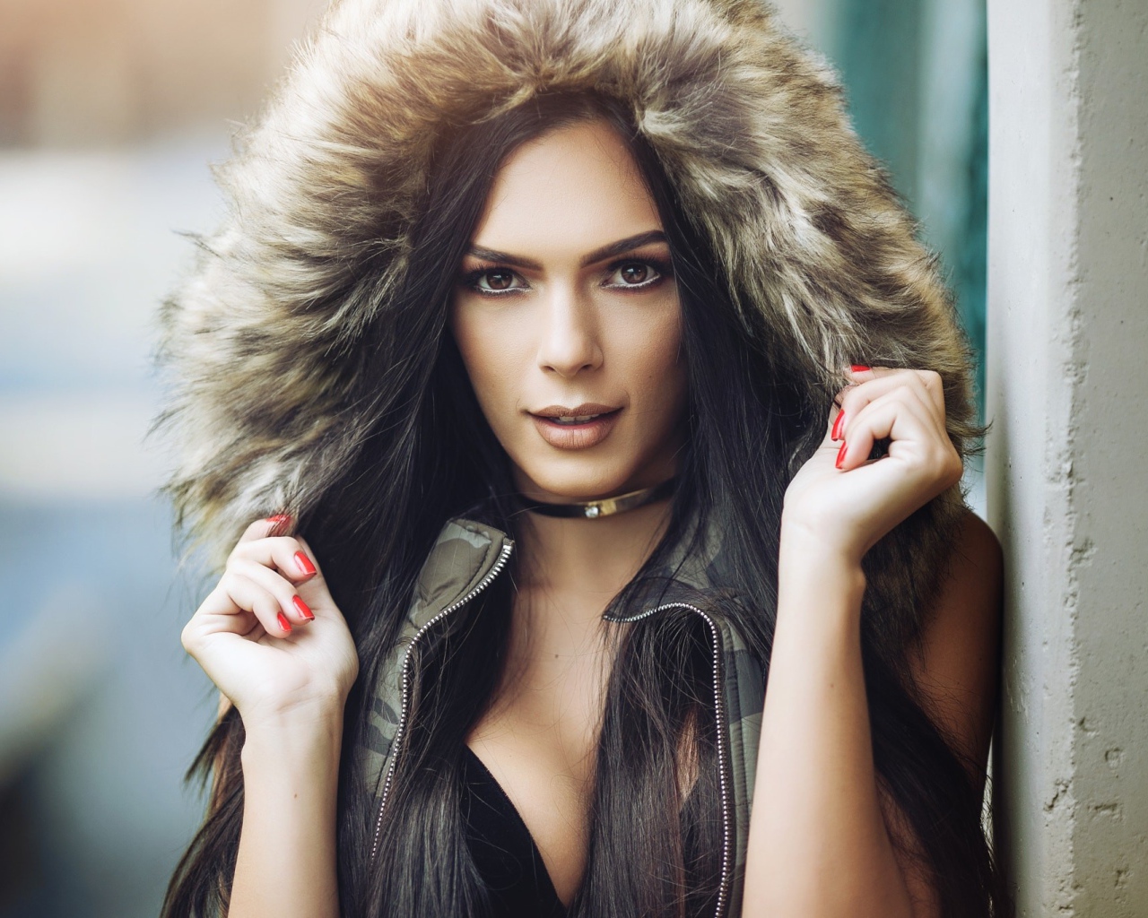 Брюнетка в капюшоне с красными ногтями на руках 