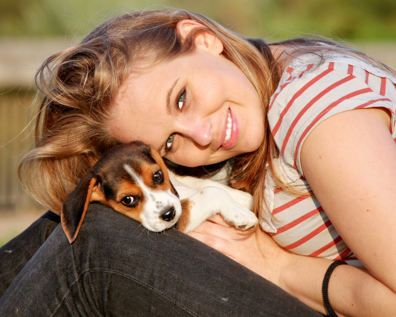 Убающаяся девушка шатенка с милым щенком на руках