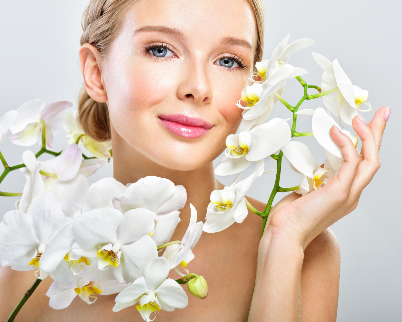Нежная голубоглазая девушка с цветами орхидеи в руках