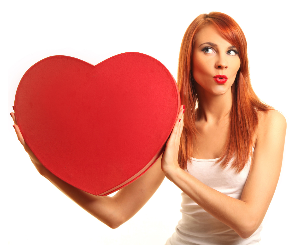 Рыжеволосая девушка с большим красным сердцем в руках на белом фоне