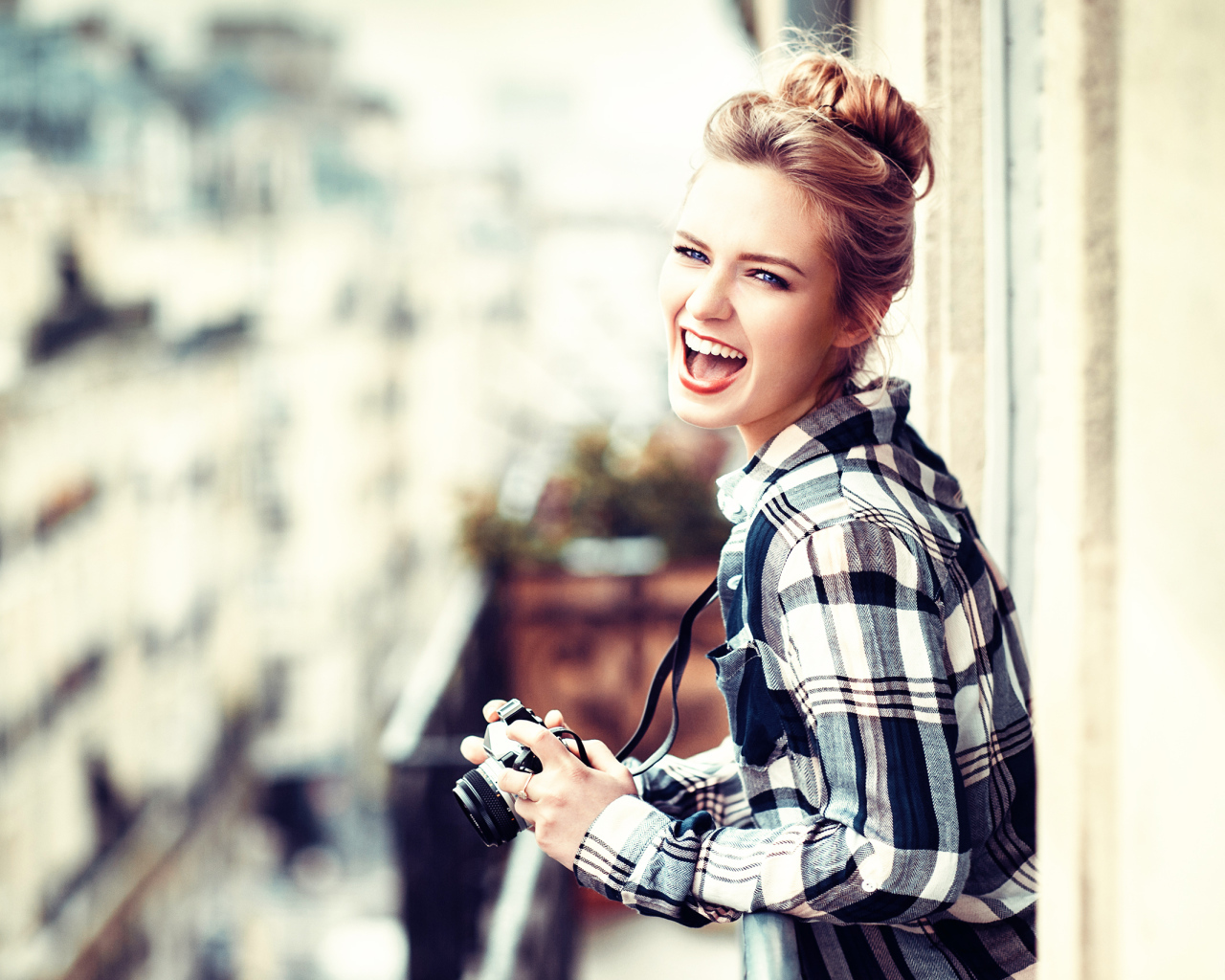Улыбающаяся девушка в клетчатой рубашке с фотоаппаратом 
