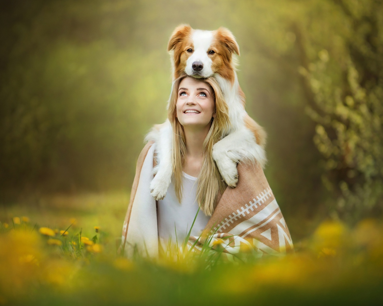 Улыбающаяся девушка с собакой сидят на траве