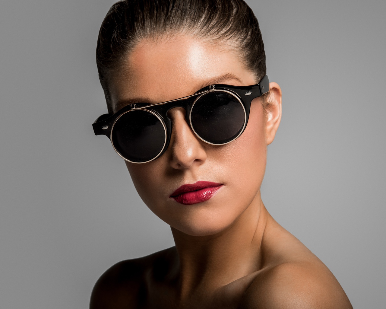 Лицо девушки в черных очках на сером фоне