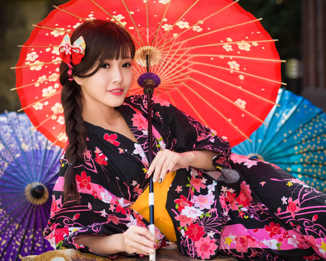 Молодая азиатка в кимоно с разноцветными зонтиками