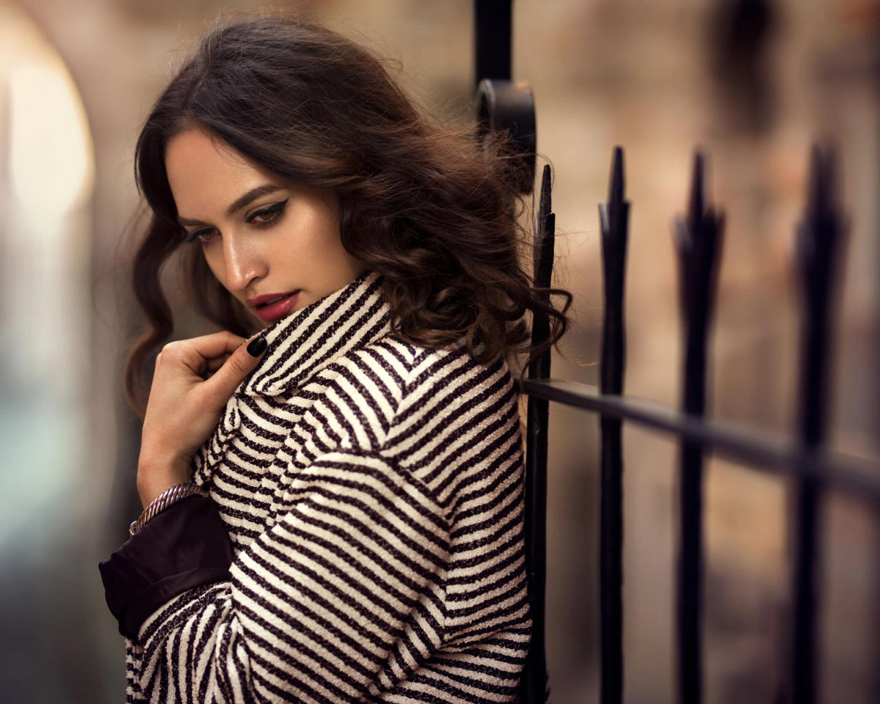 Молодая брюнетка в пальто у забора