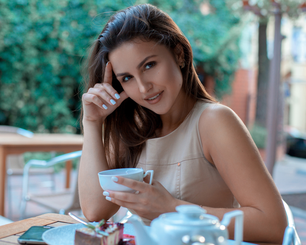 Молодая улыбающаяся девушка с чашкой кофе в кафе