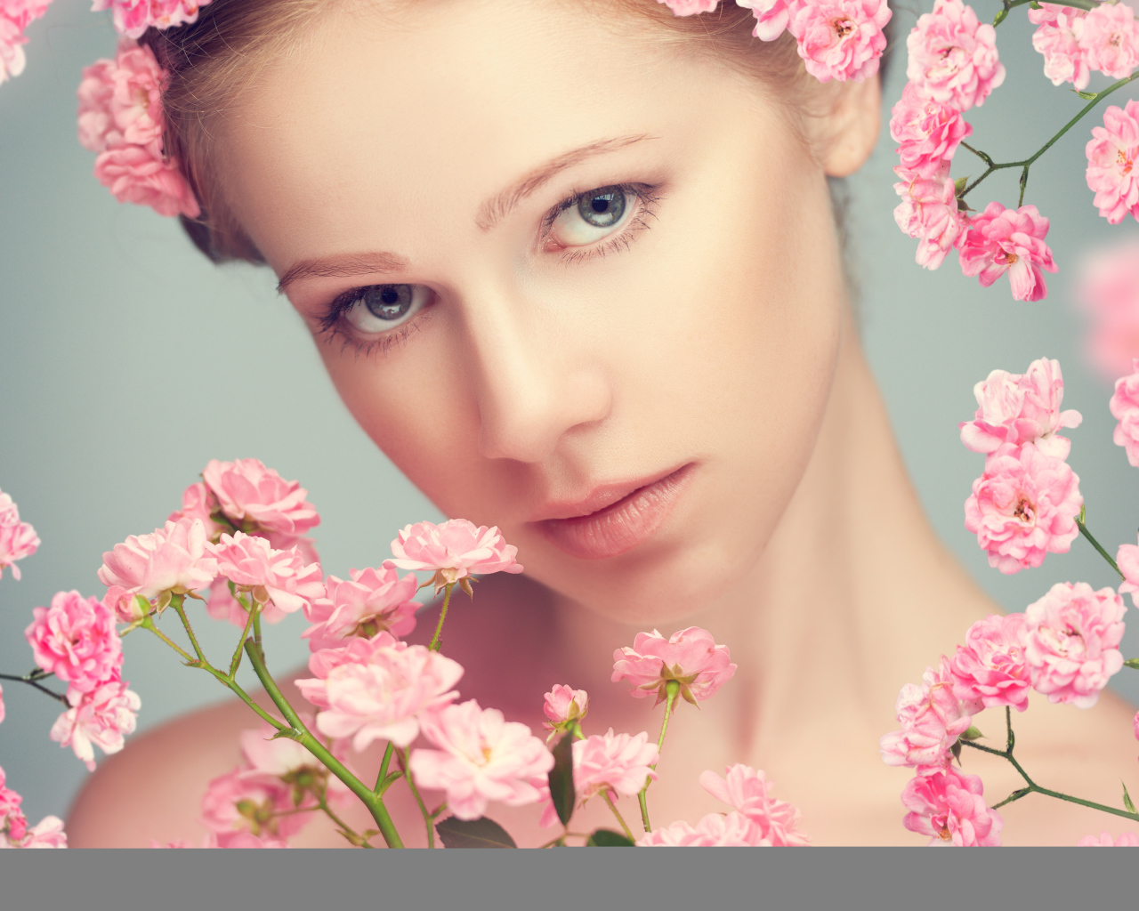 Молодая нежная девушка с розовыми розами на сером фоне