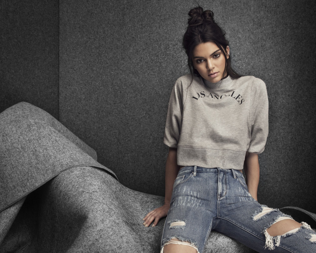 Модель Кендалл Дженнер в рваных джинсах на сером фоне