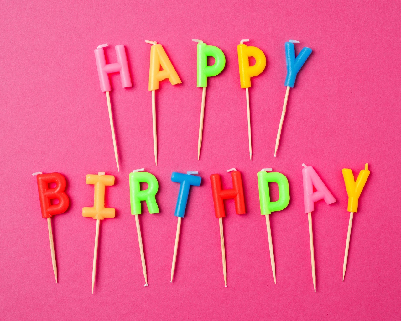 Праздничные свечи с надписью Happy Birthday на розовом фоне