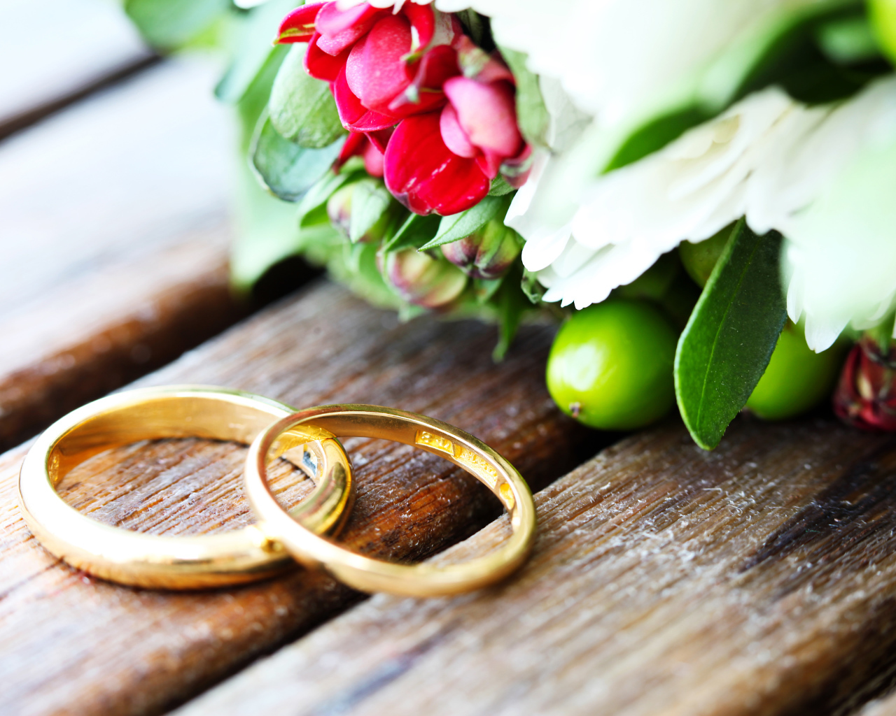 Two gold wedding rings with a bouquet of flowers