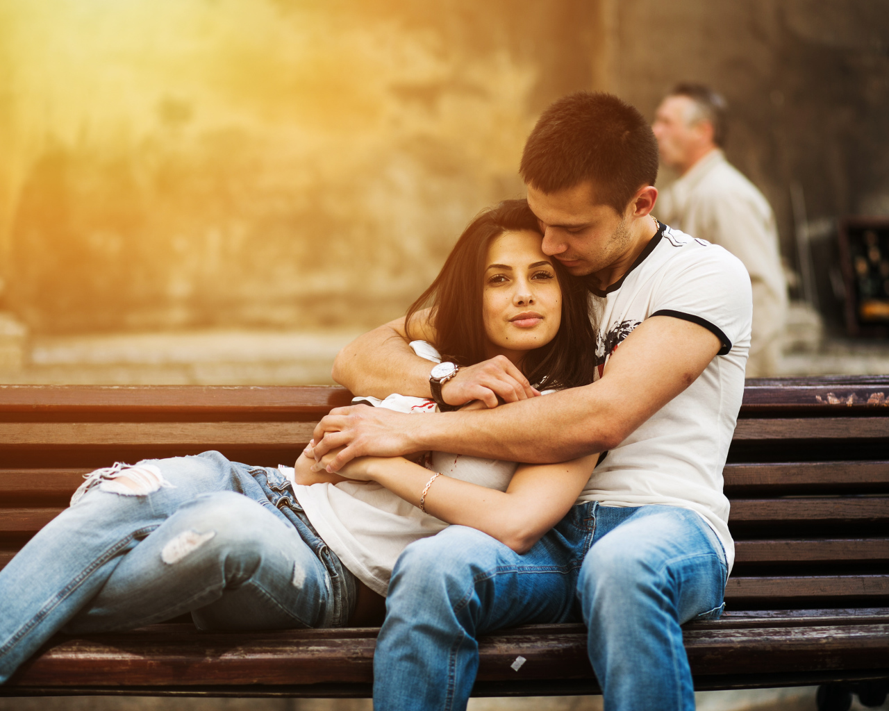 Влюбленная пара сидит на деревянной лавке в парке