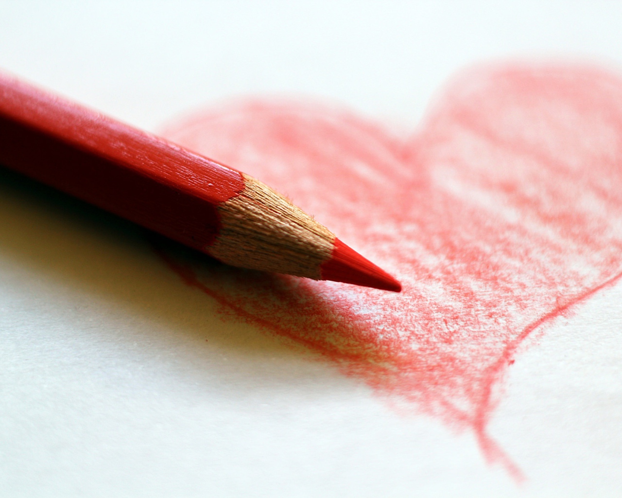 Нарисованное карандашом красное сердце на бумаге