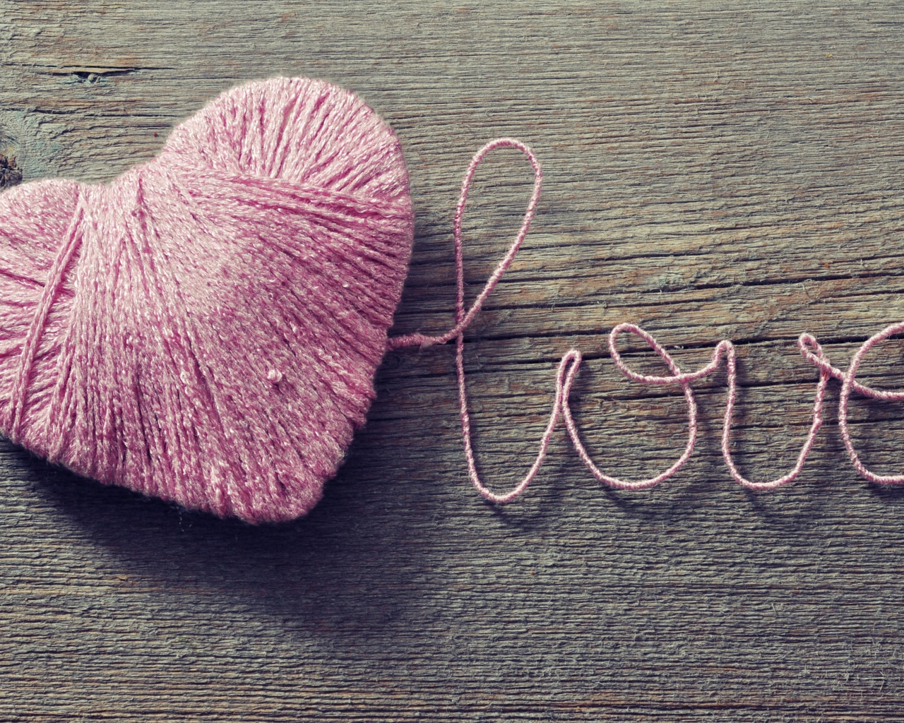 Надпись Love из розовых ниток на деревянном столе