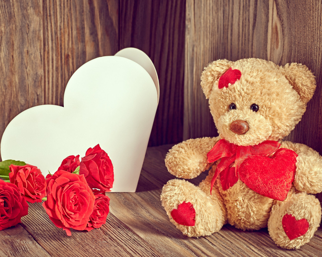 Плюшевый медведь с большим белым бумажным сердцем и красными розами