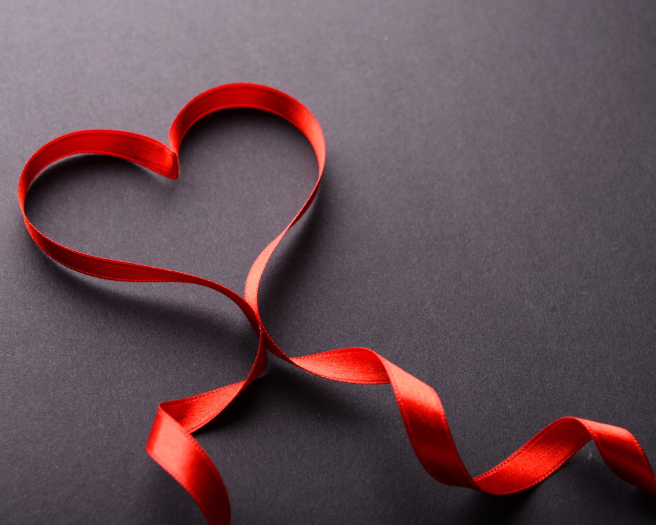 Красное сердце из атласной ленты на сером фоне