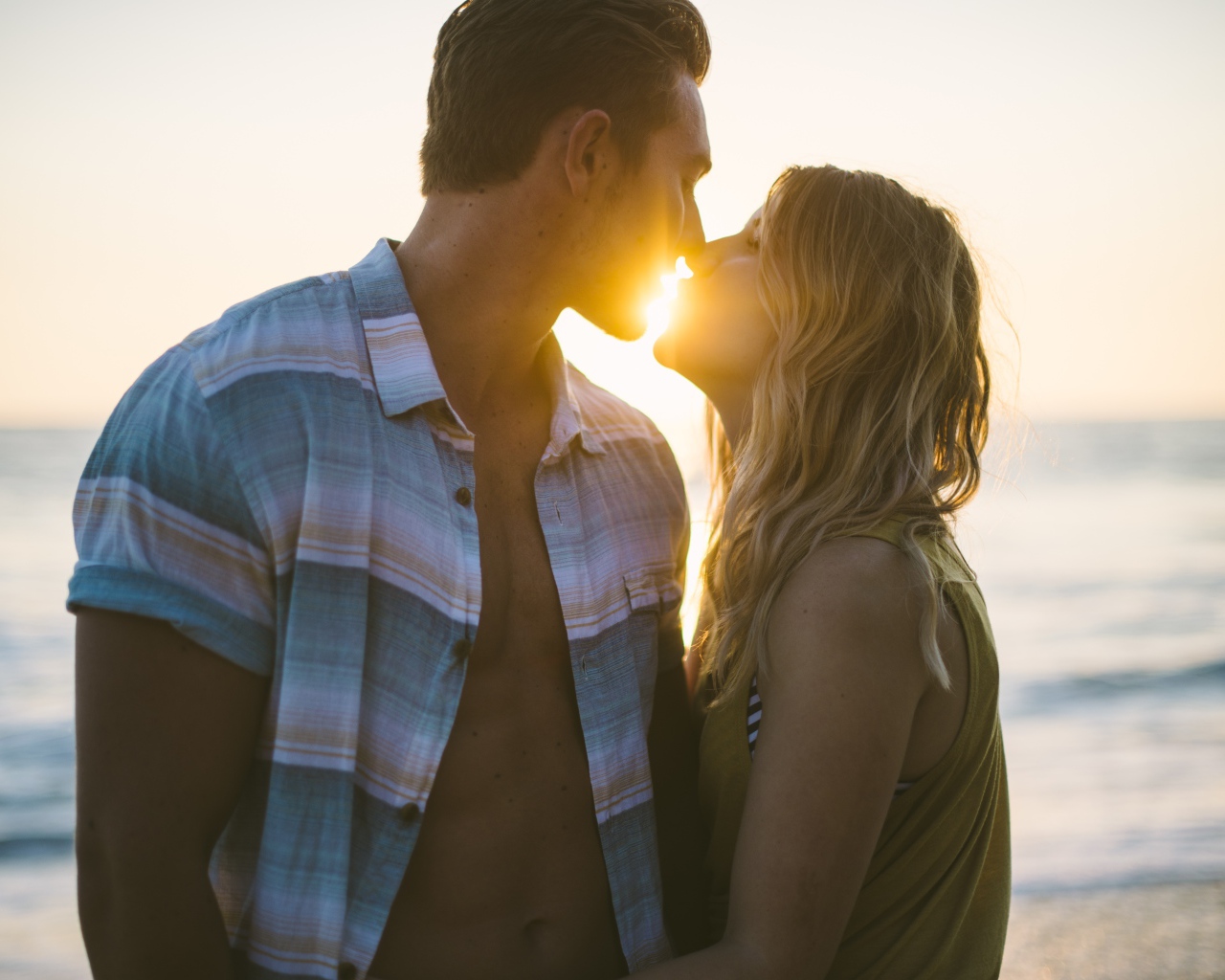 Романтический поцелуй влюбленной пары на закате солнца