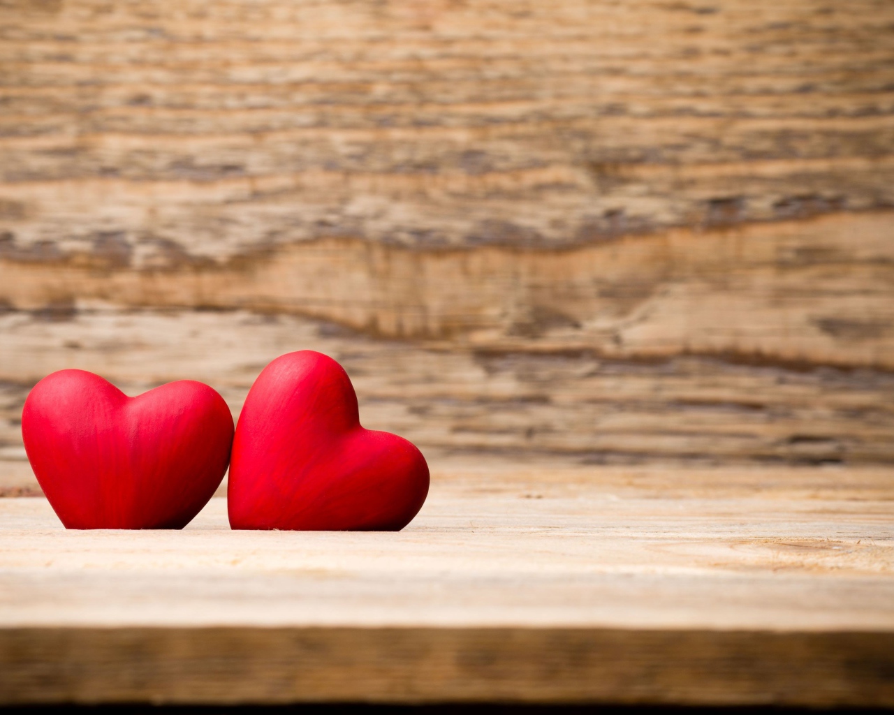 Два красных сердца лежат на деревянной лавке