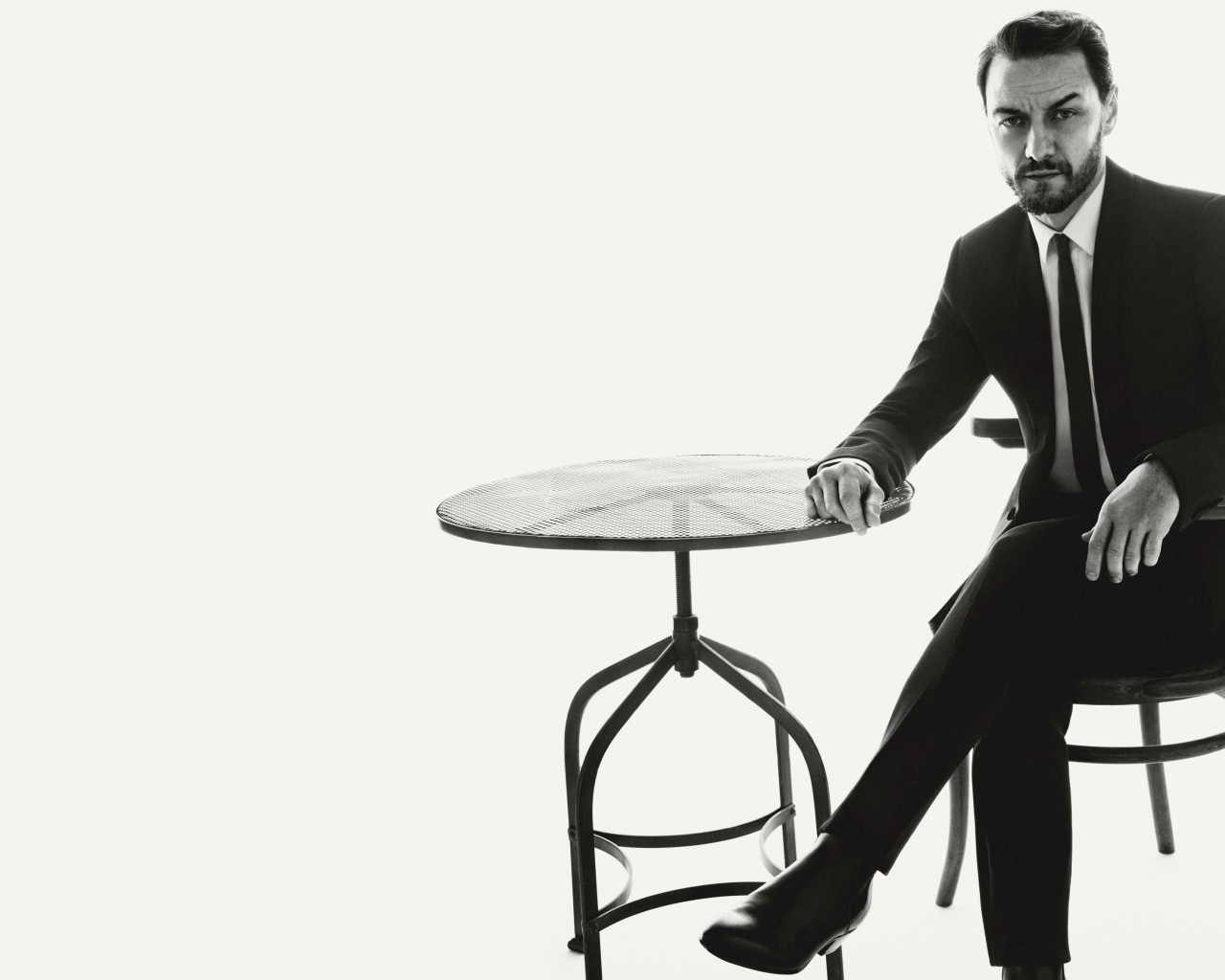 Актер Джеймс Макэвой сидит на стуле за столом черно-белое фото