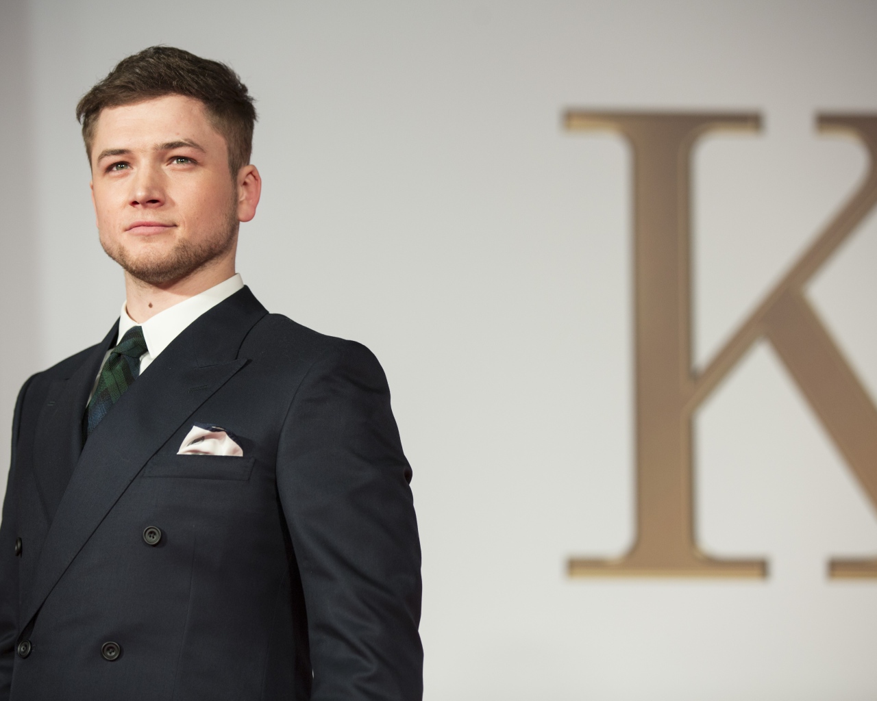 Молодой актер Терон Эгертон в черном пиджаке