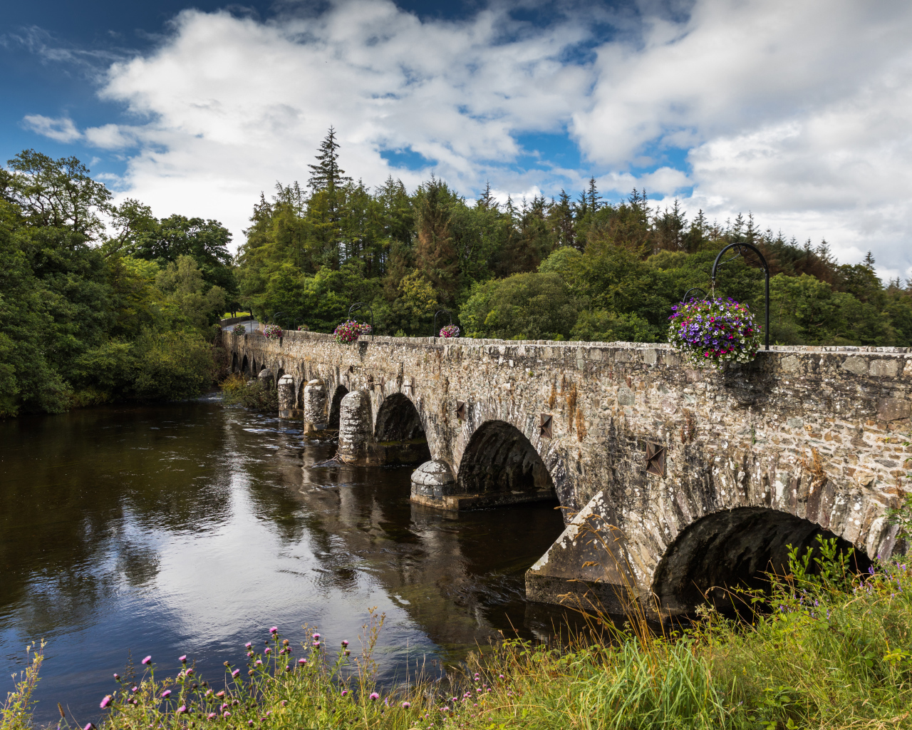 Мост через реку у леса на фоне красивого голубого неба с белыми облаками. Ирландия