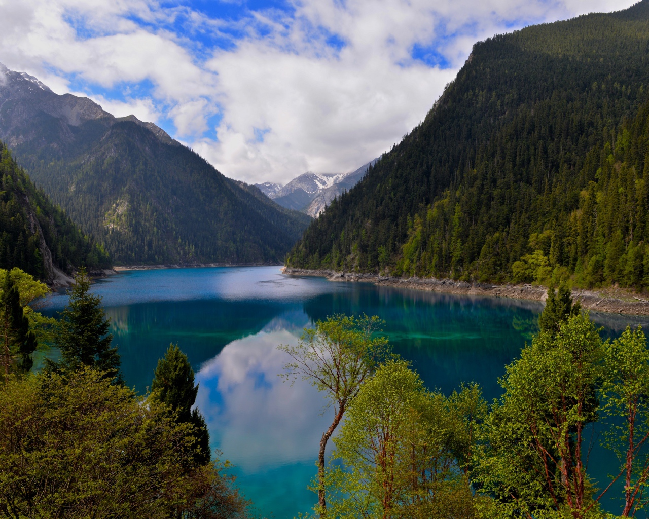 Красивое озеро у покрытых лесом гор в парке Цзючжайгоу, Китай