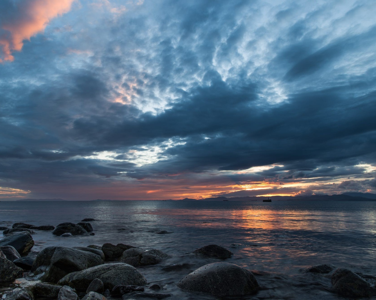 Валуны в воде на берегу на фоне пасмурного неба 