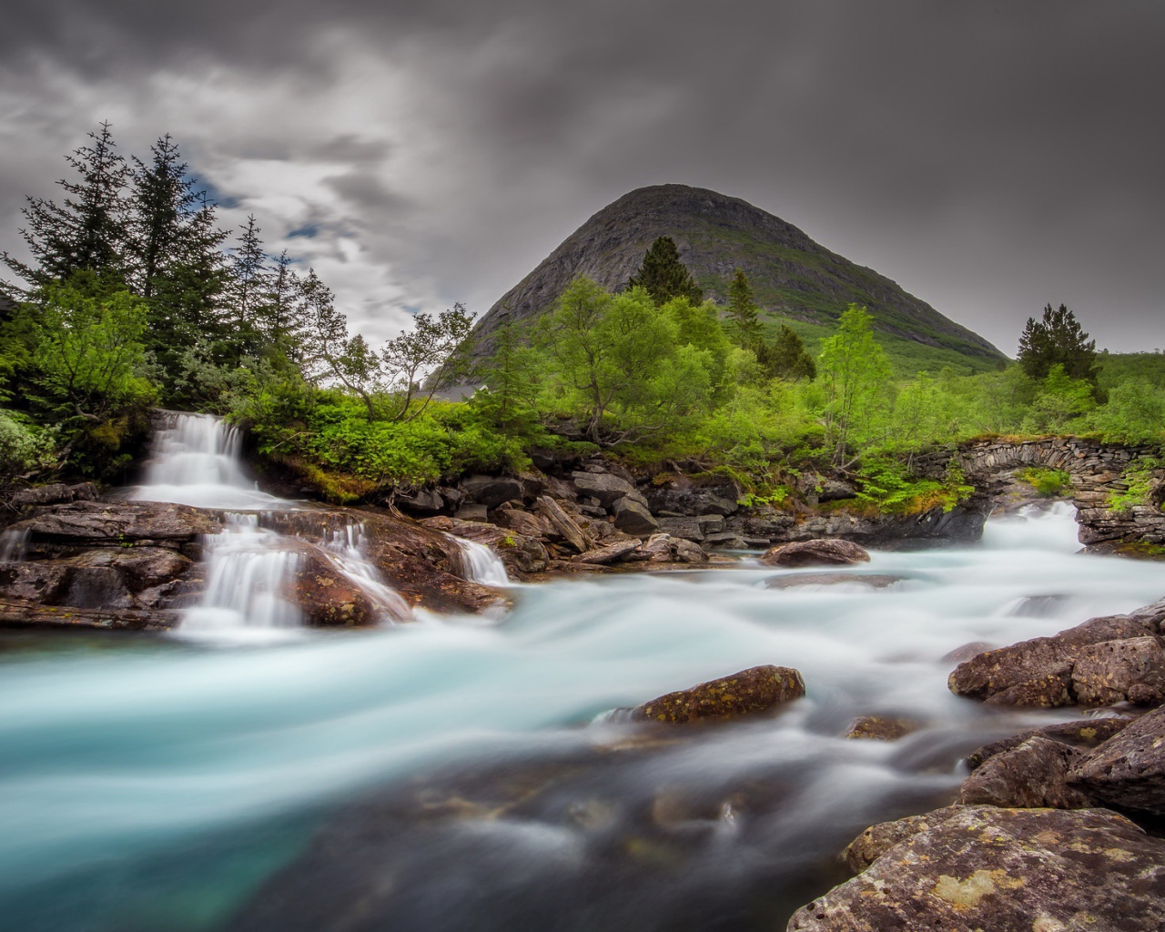 Быстрая вода в горной реке с маленьким водопадом 