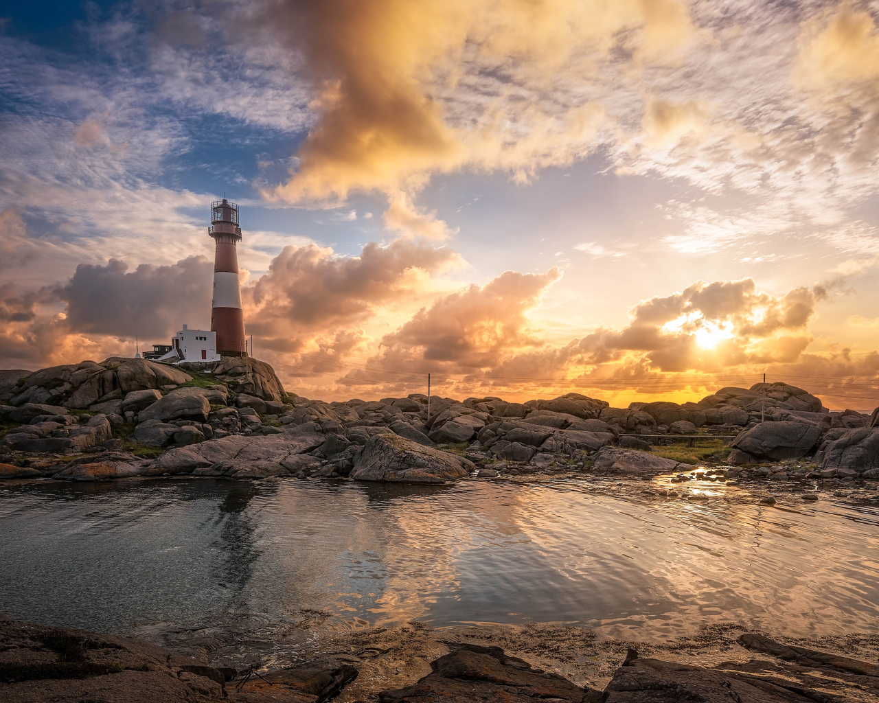 Маяк на каменном побережье на фоне красивого неба