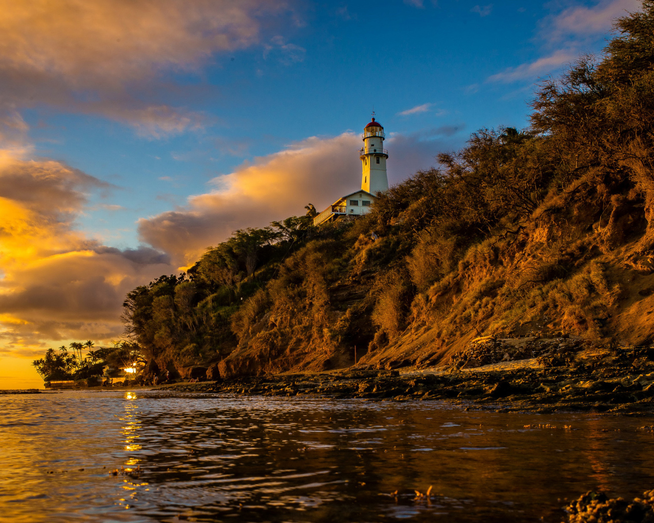 Маяк на склоне скалы на закате 