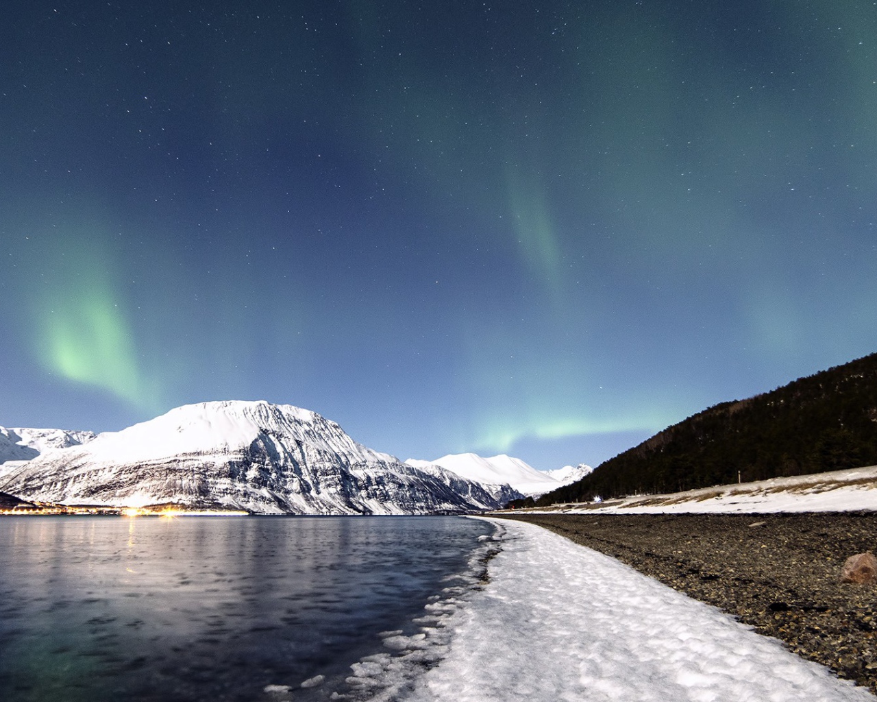 Северное сияние в небе над заснеженными горами 