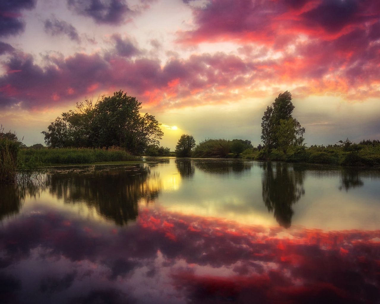 Красные облака отражаются в чистой воде реки