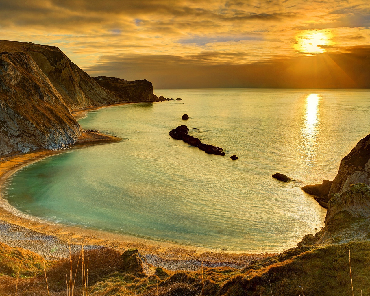 Скалы на берегу океана в лучах солнца на закате