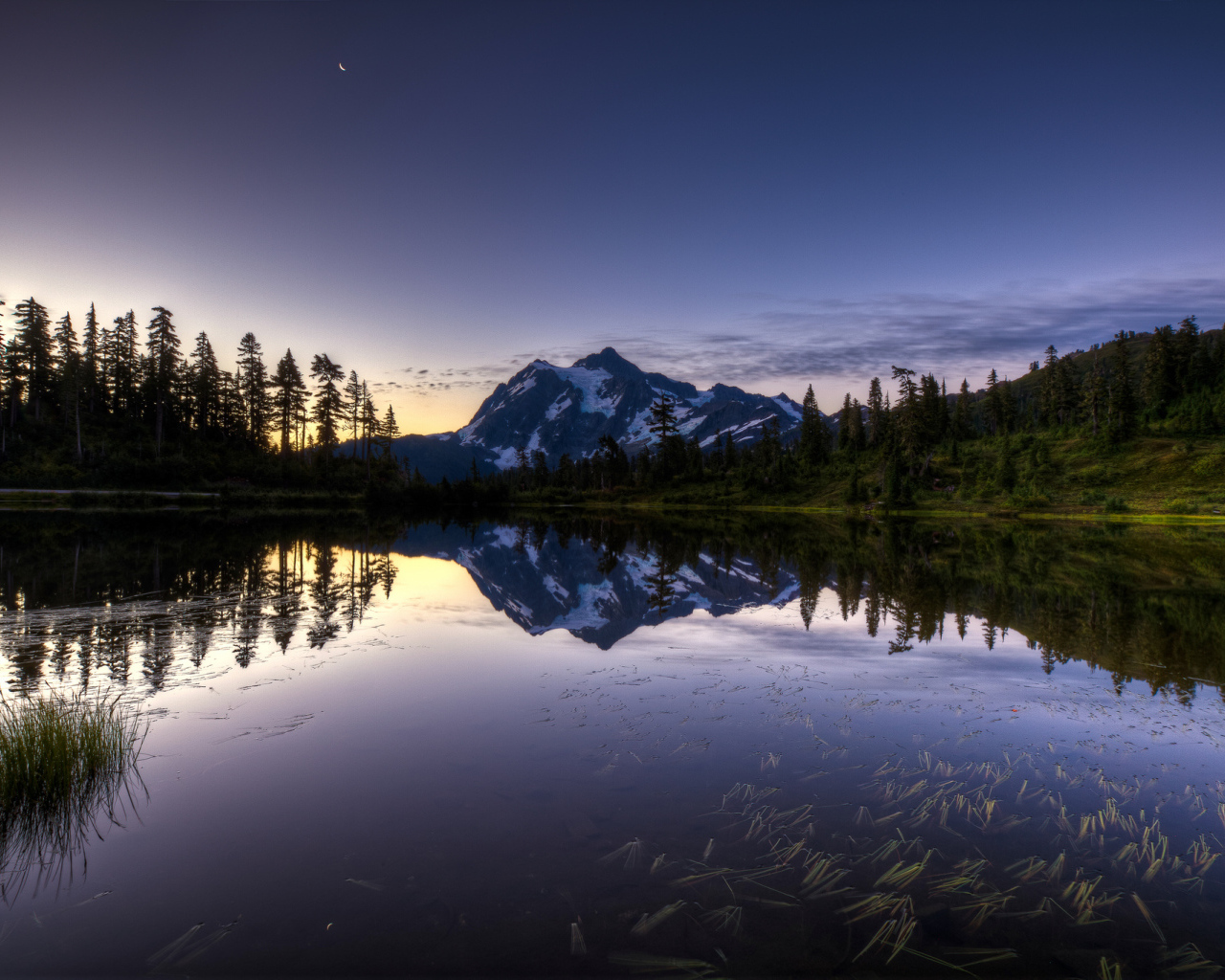 Заснеженная гора и лес отражается в озере вечером