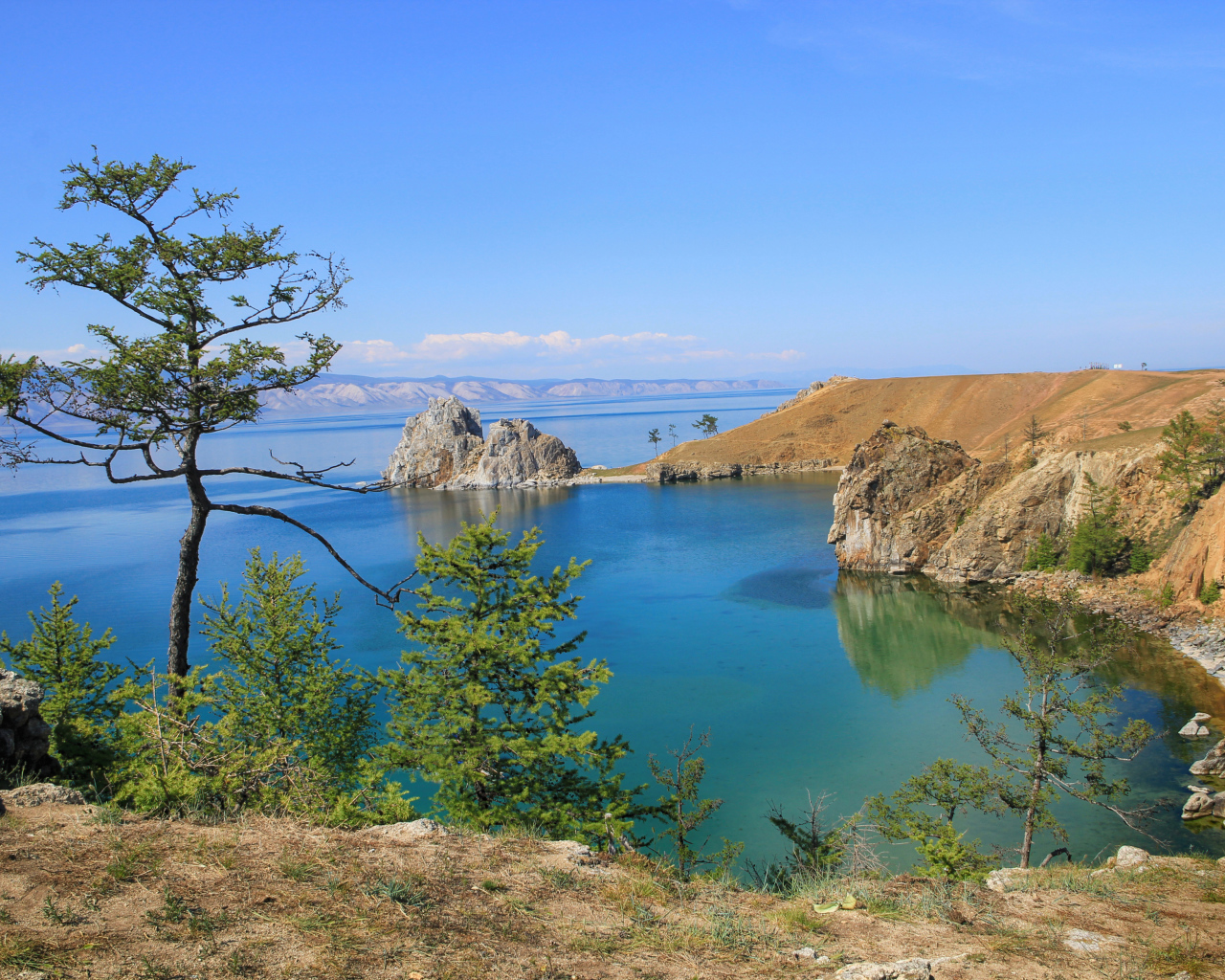 Каменные утесы у чистой воды живописного озера Байкал,  Россия