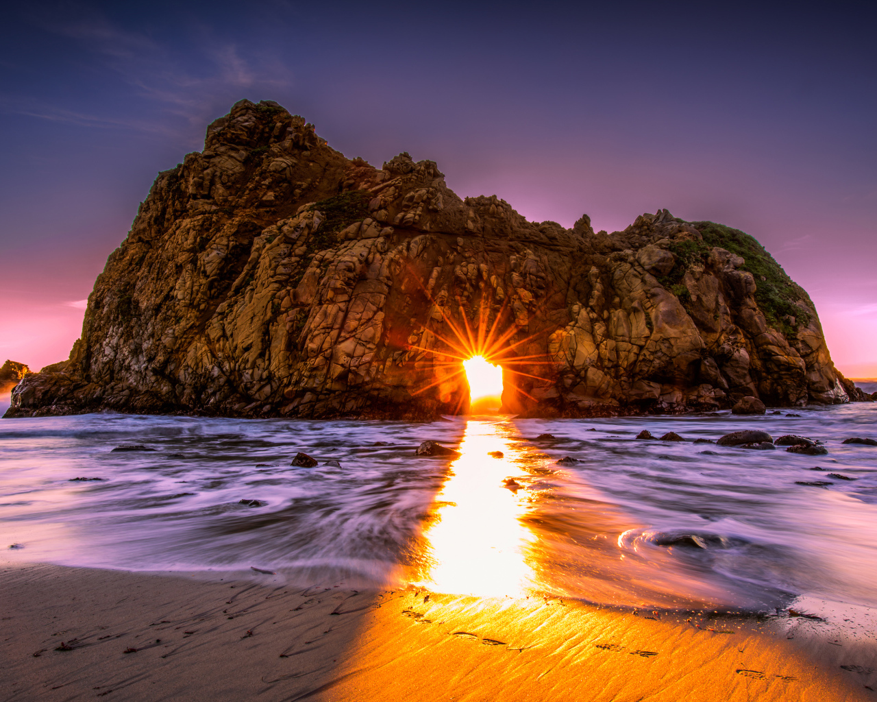 Лучи солнца пробиваются сквозь отверстие в скале  Pfeiffer Beach Big Sur, Калифорния  