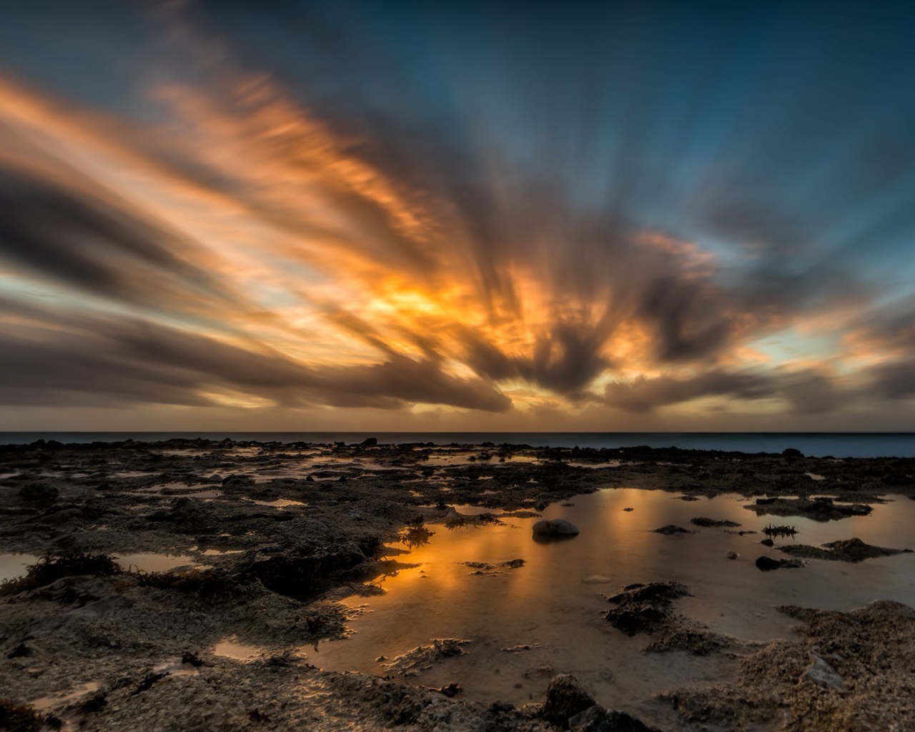 Закат солнца в облаках над водой 