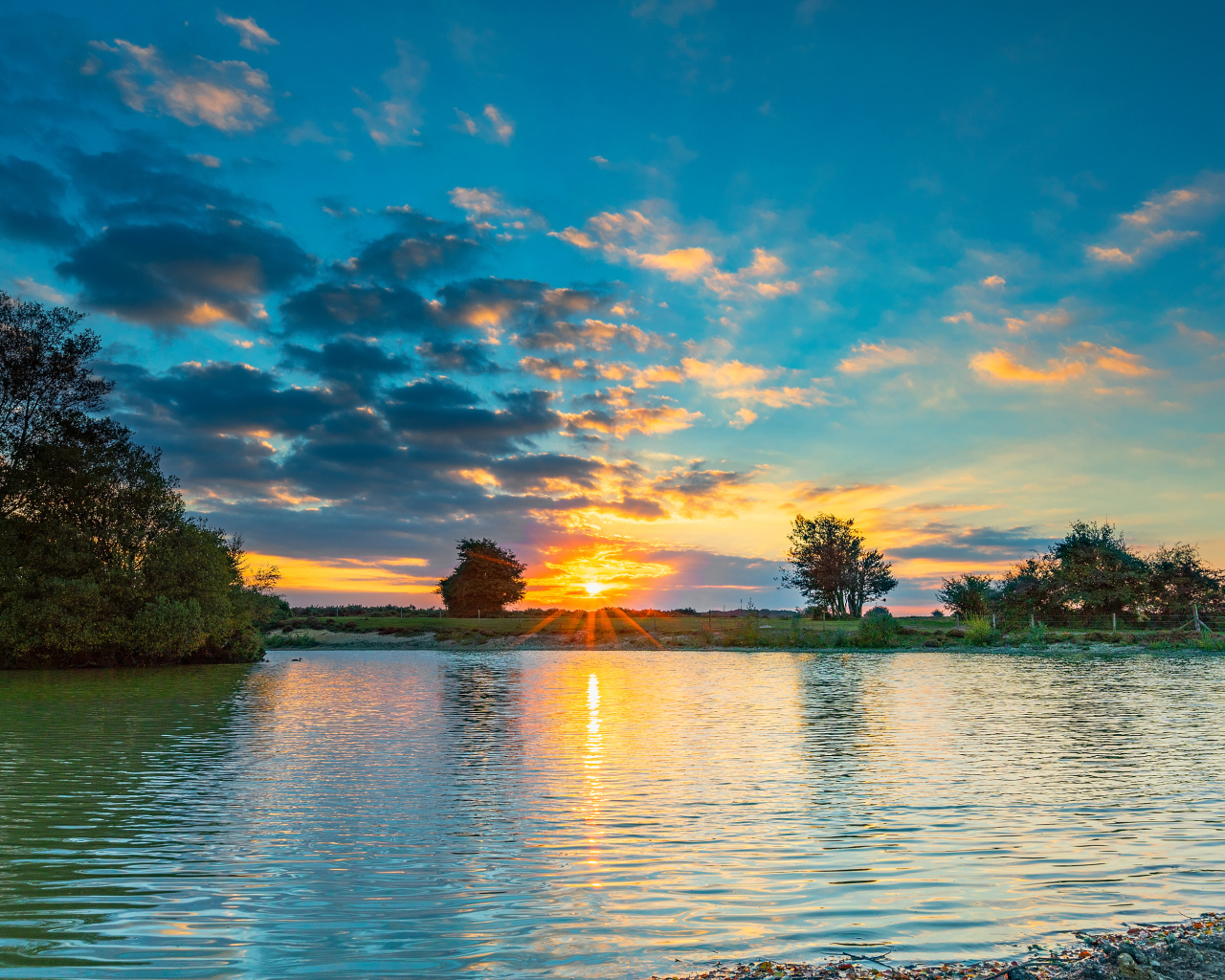 Закат солнца в небе отражается в воде озера 